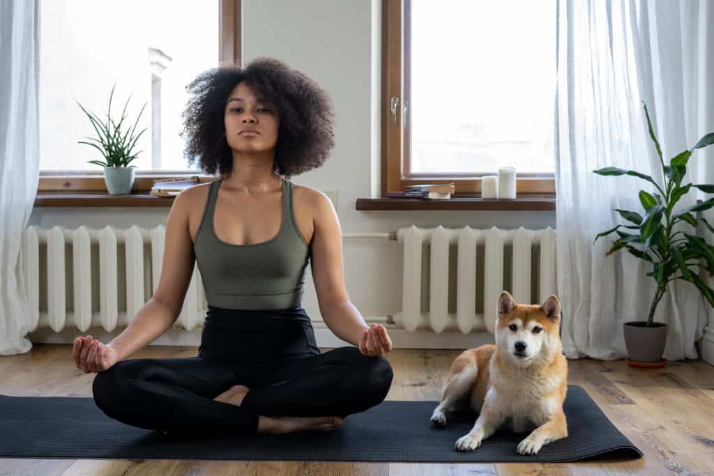 Naine joogamatil mediteerimas koos koeraga